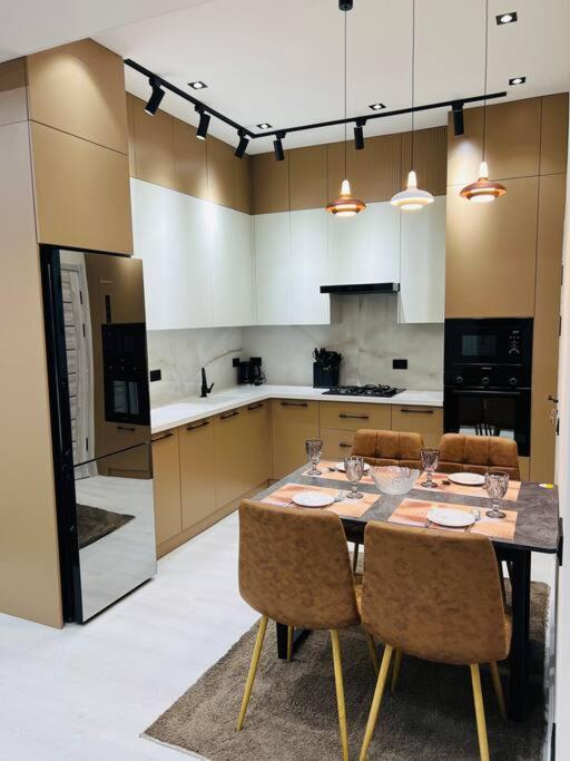 una cocina con mesa con sillas y una cocina con armarios blancos. en 3-roomed apartment close to the REGISTAN Ozod Apartments en Samarcanda
