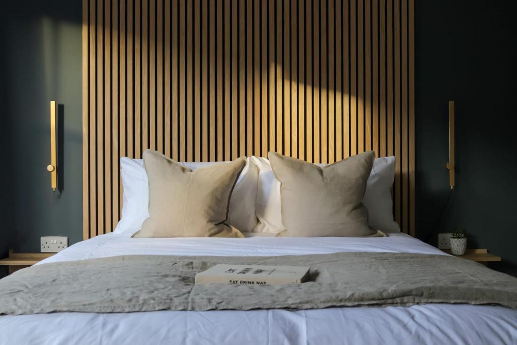 ein Bett mit weißen Kissen und ein Buch darauf in der Unterkunft Beautiful Oxford Townhouse near City Centre in Oxford