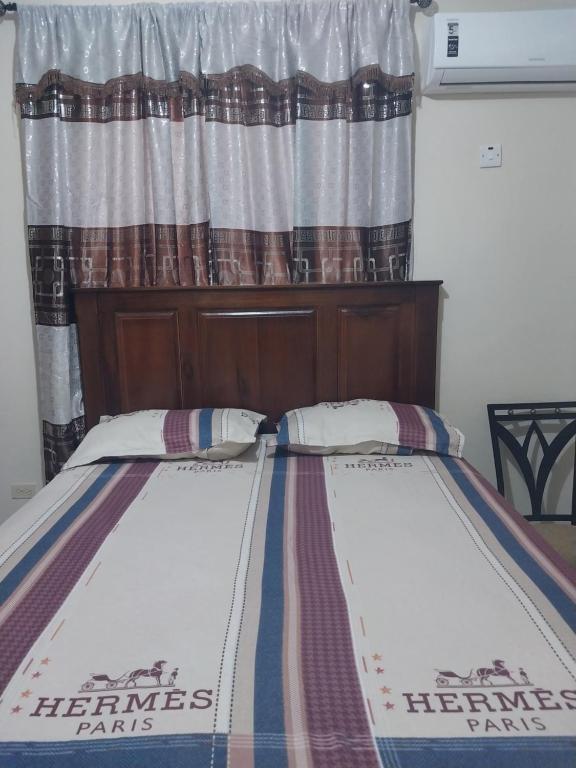 a bed in front of a window with a bedspread at Monet's sweet Haven in Spanish Town