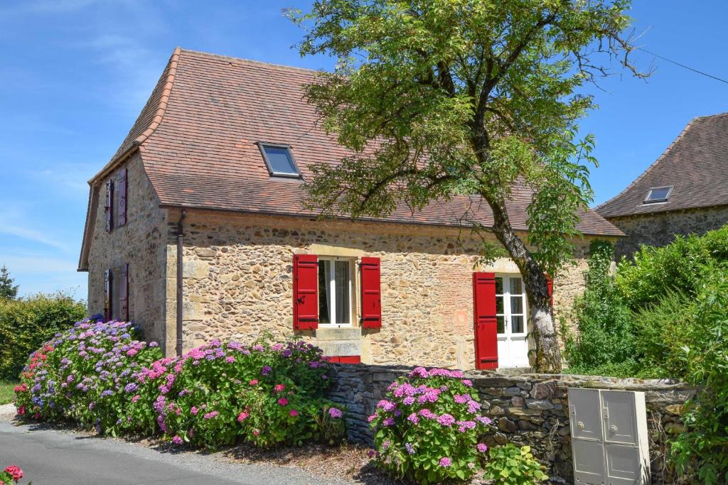 a stone house with red shutters and flowers at Domaine d&#39;Essendiéras in Saint-Médard-dʼExcideuil