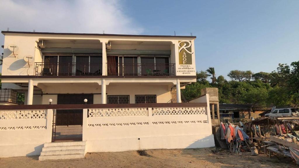 a white building with a balcony on top of it at Annexe RAOOF HOTEL in Mahajanga