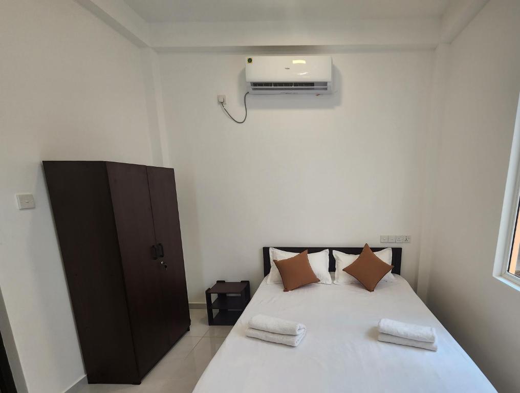 um quarto com uma cama branca e 2 almofadas em Joywin Apartments Airport transit em Negombo
