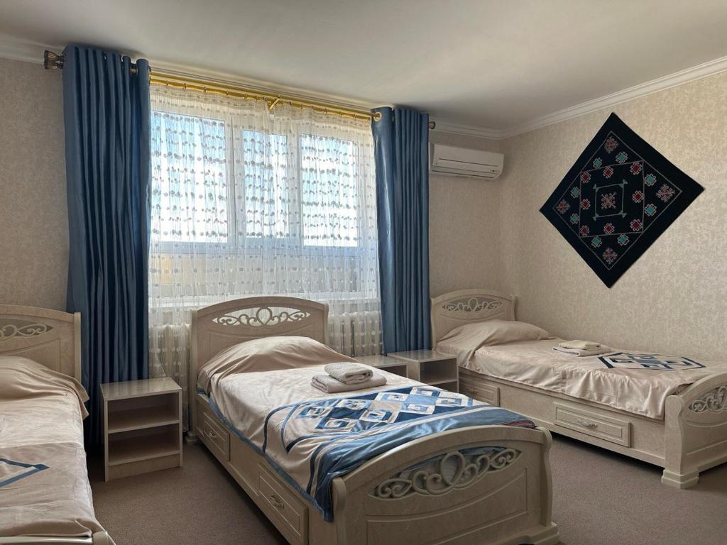 1 dormitorio con 2 camas y ventana en Guest house "NIKA", Nukus, en Nukus