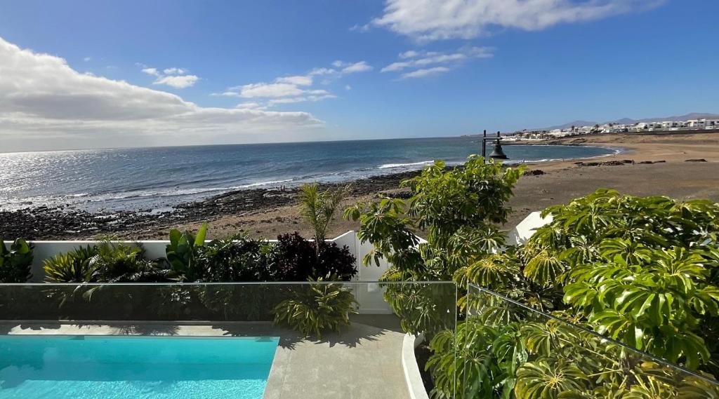 a swimming pool next to a beach with the ocean at Villa del Mar Lanzarote - Luxury Beachhouse in Arrecife