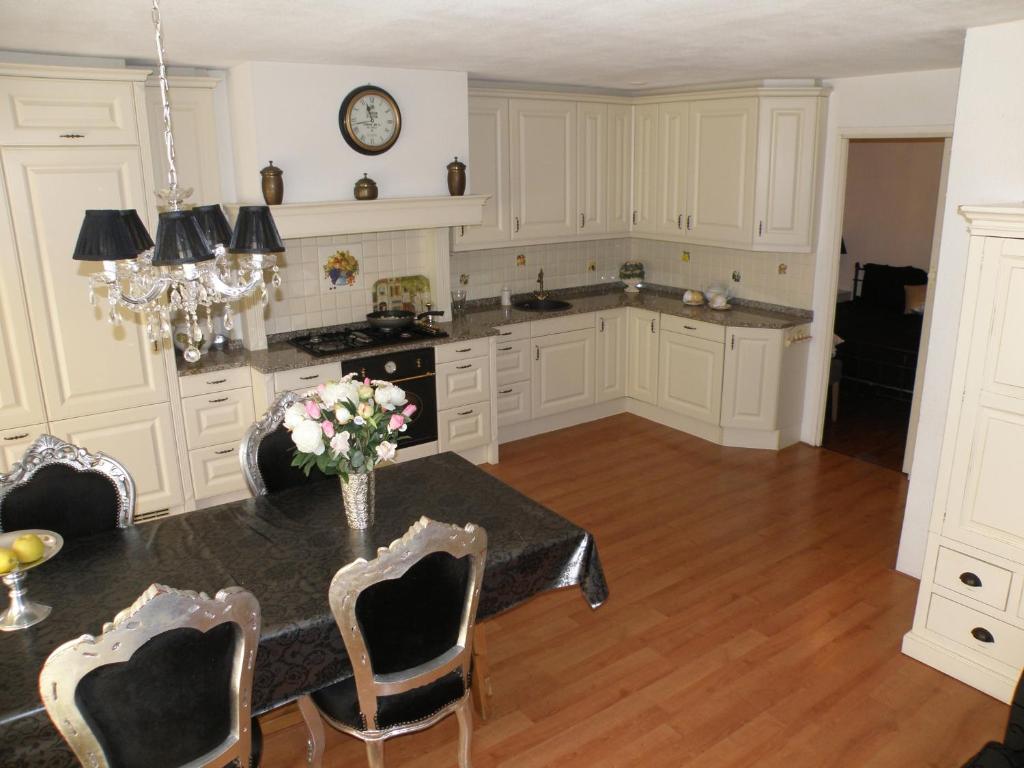 una cocina con armarios blancos y una mesa con flores. en Apartment Seastar Zandvoort, en Zandvoort