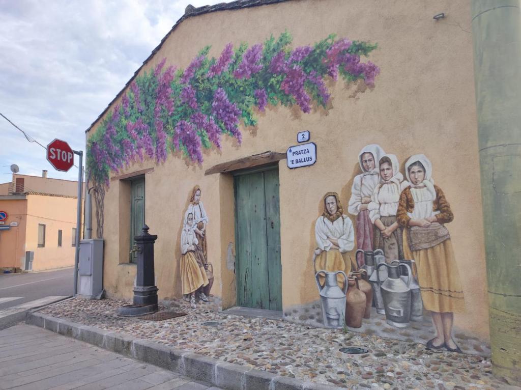 une fresque représentant un groupe de personnes sur le côté d'un bâtiment dans l'établissement Casa Lalletta, à Nurachi