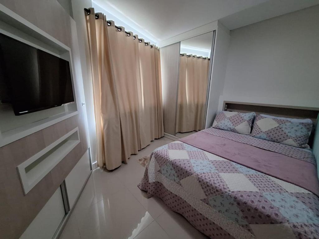 ein kleines Schlafzimmer mit einem Bett und einem Flachbild-TV in der Unterkunft Cobertura Ap praia de Bombas in Bombinhas