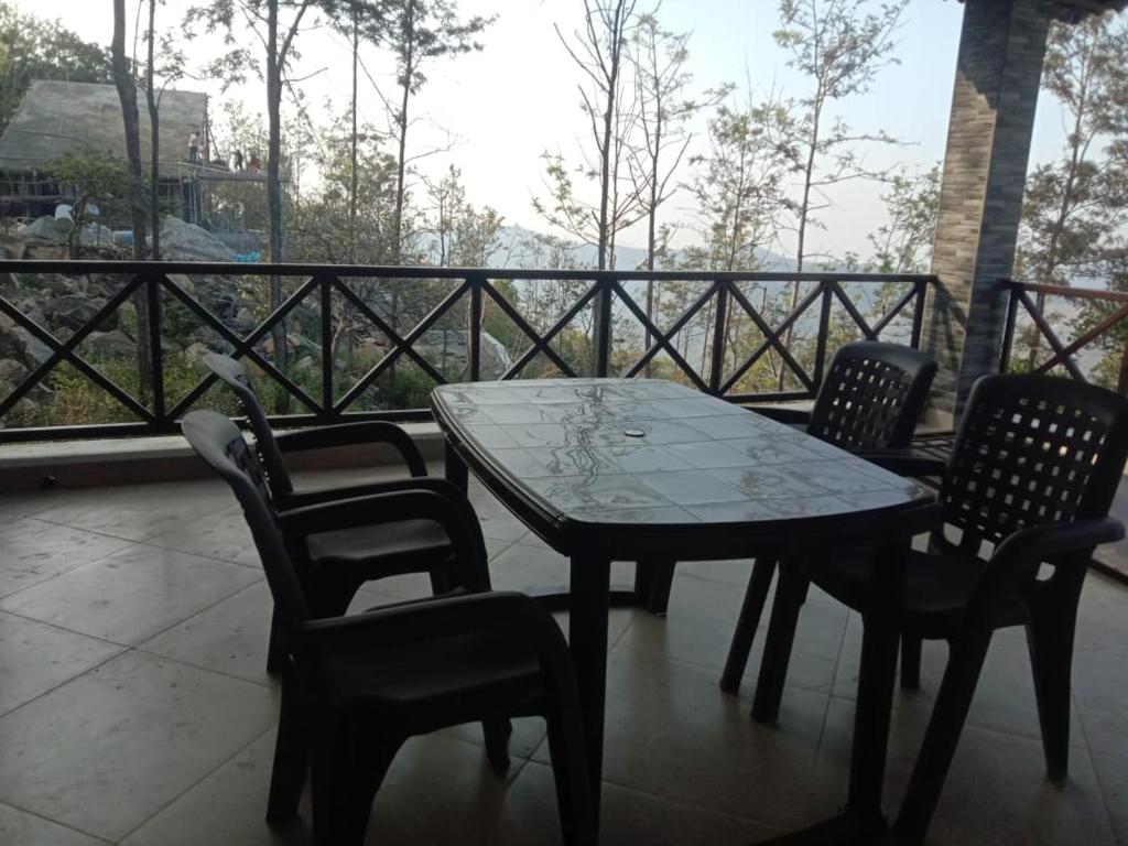 a table and chairs on a balcony with a view at Tulip in green meadows in Yercaud