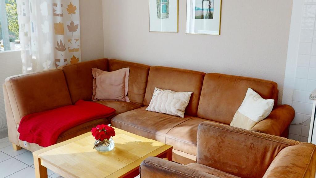 ein Wohnzimmer mit einem braunen Sofa und einem Tisch in der Unterkunft Gilde-Residenz App. 1 in Grömitz