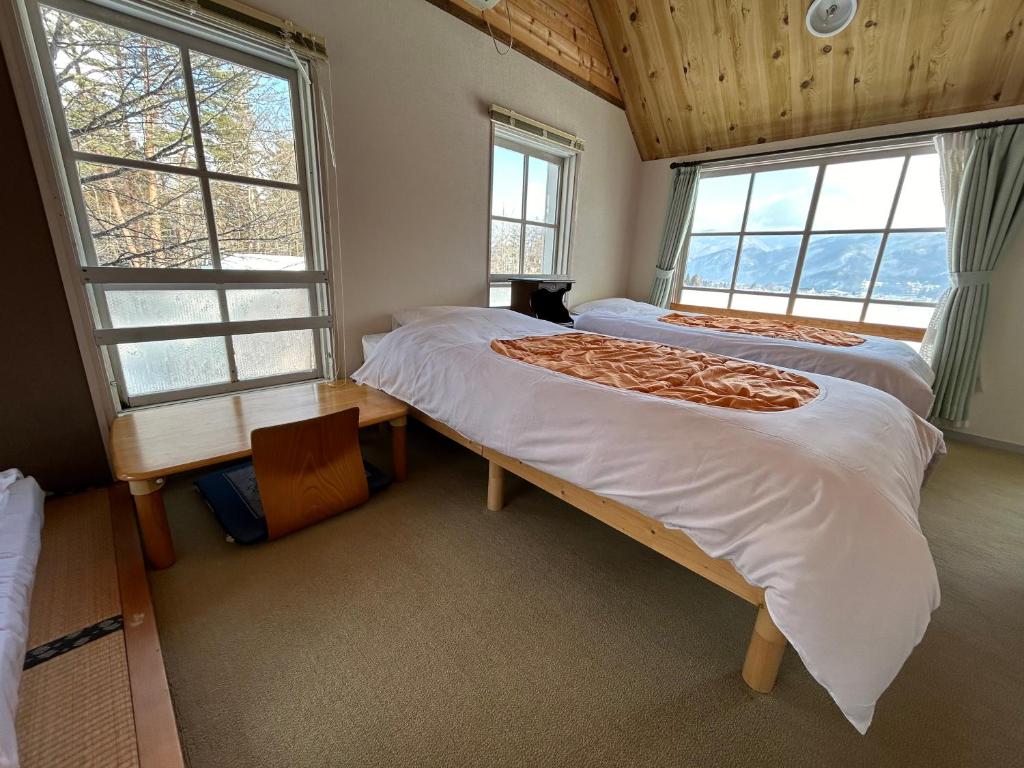 a bedroom with two beds and two windows at Hakuba Snow Fox in Hakuba