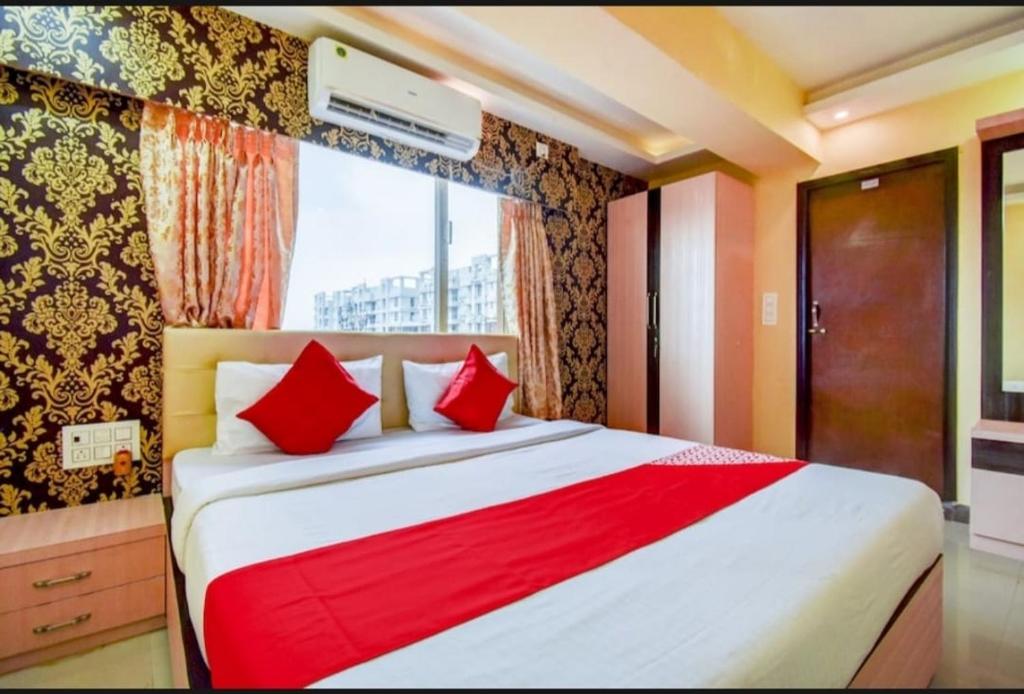 Hotel Deep Chinarpark,Near kolkata airport في Salua: غرفة نوم بسرير ومخدات حمراء ونافذة