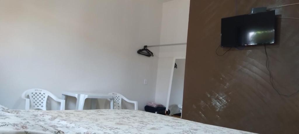 a bedroom with a table and chairs and a tv on the wall at kitnet Marilia 2 in Marília