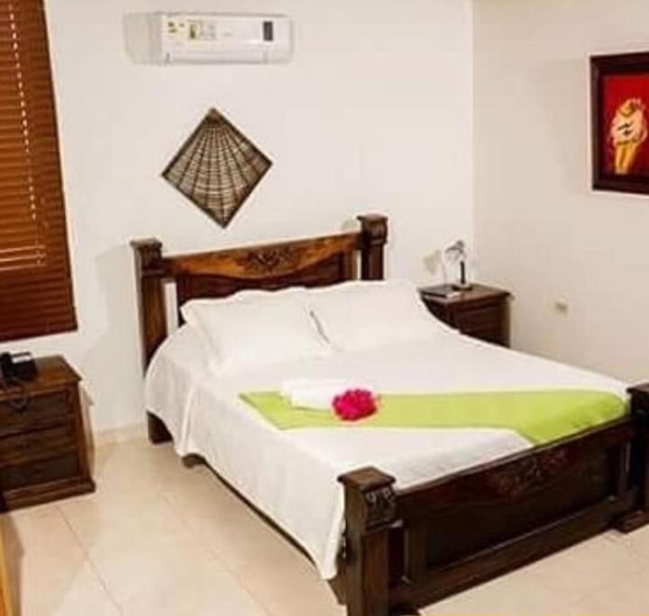 a bedroom with a bed with a red flower on it at Hotel La Casona Vieja in Valledupar