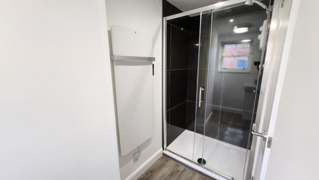 La salle de bains est pourvue d'une douche et d'une porte en verre. dans l'établissement Bridge Street Apartments, à Peterborough