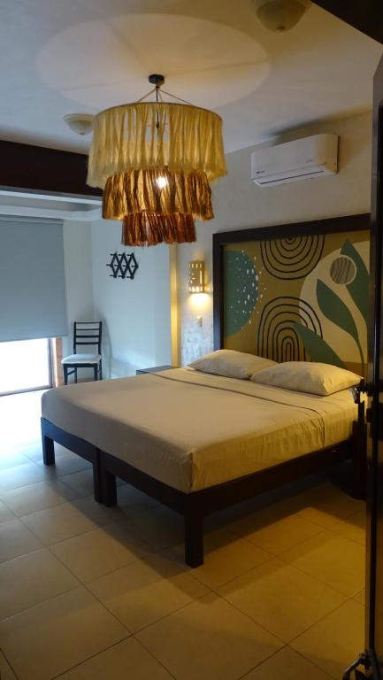 a bedroom with a large bed with a chandelier at Hotel Boutique Kinich in Isla Mujeres