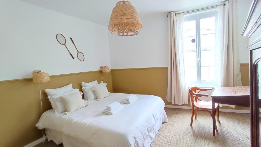 a bedroom with a white bed with a desk and a window at Maison Charmeilles - La suite Saint Emilion in Fronsac