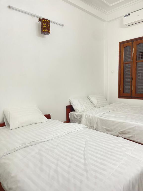 two beds in a room with white sheets at Agarwood in Hanoi