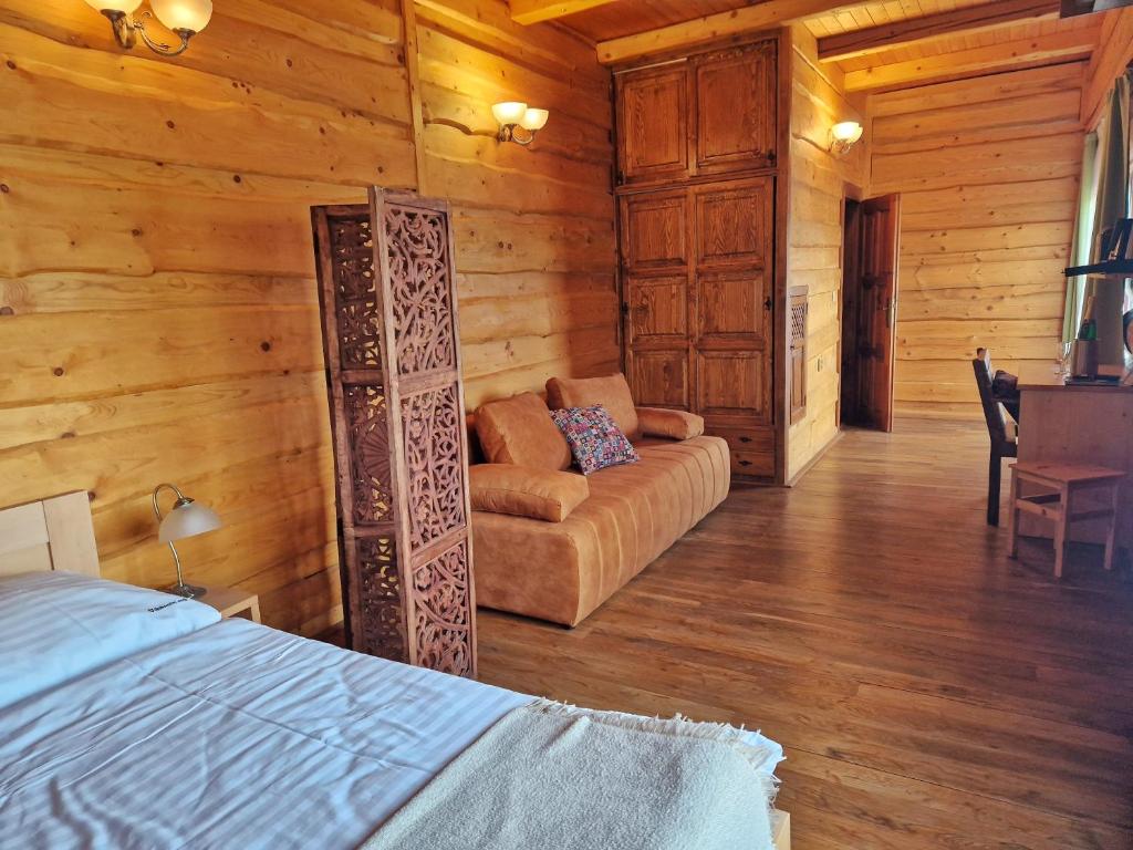 um quarto com uma cama e um sofá numa cabana de madeira em Sport-hotel Šibeniční vrch em Mnichovice
