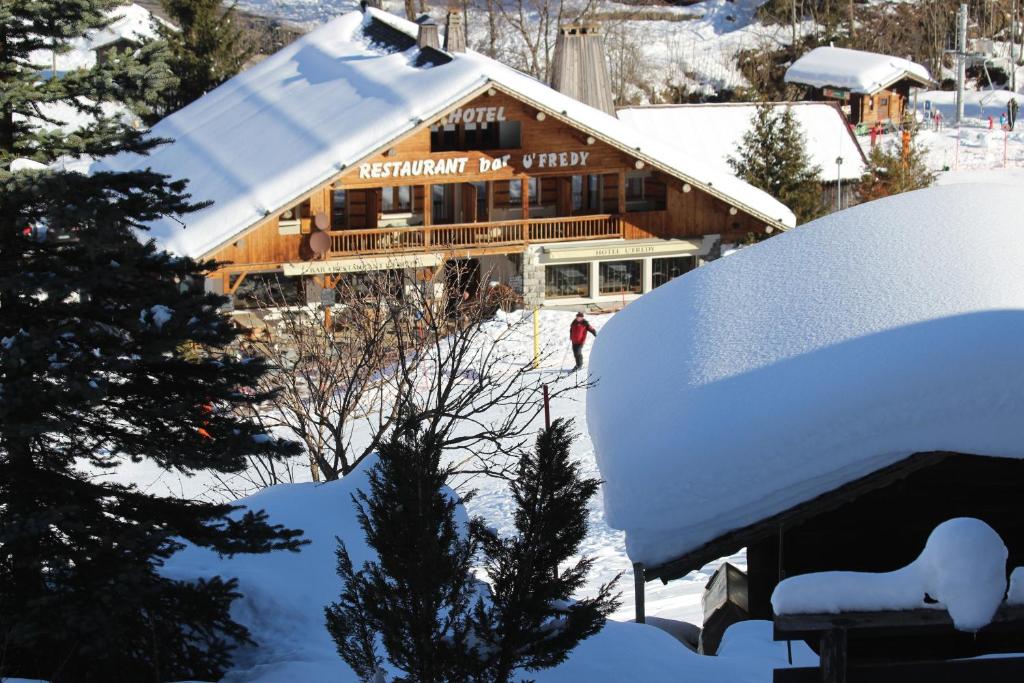 Cabaña de madera cubierta de nieve con techo cubierto de nieve en Hôtel Restaurant U'Fredy, en La Clusaz