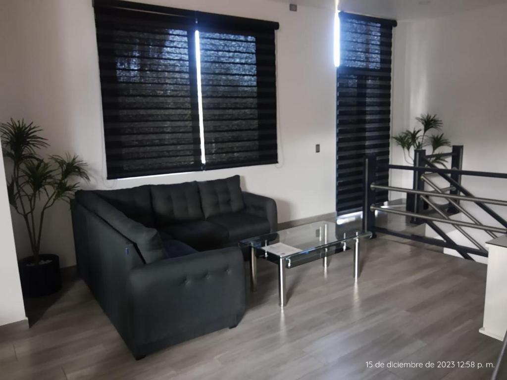 sala de estar con sofá negro y mesa de cristal en Departamento Glorieta, en Mazamitla