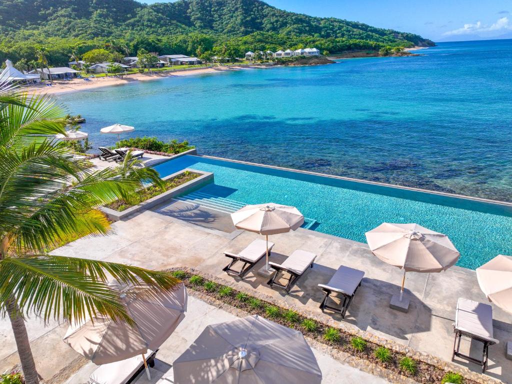 an aerial view of a pool with umbrellas and the ocean at Hawksbill Resort Antigua - All Inclusive in Five Islands Village