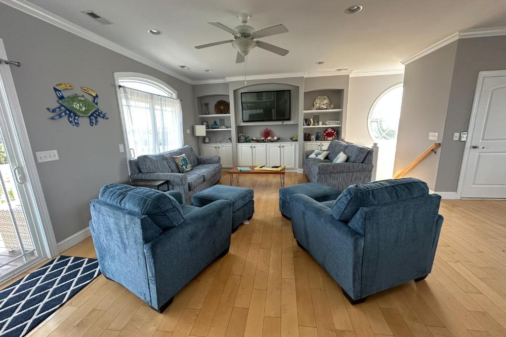 a living room with two blue chairs and a tv at Bird's Nest in Holden Beach