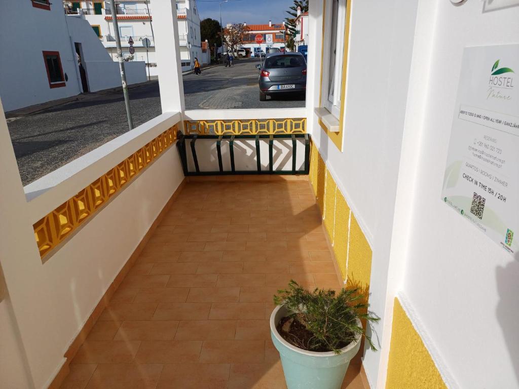 a hallway with a plant in a pot on a sidewalk at Hostel Nature in Zambujeira do Mar