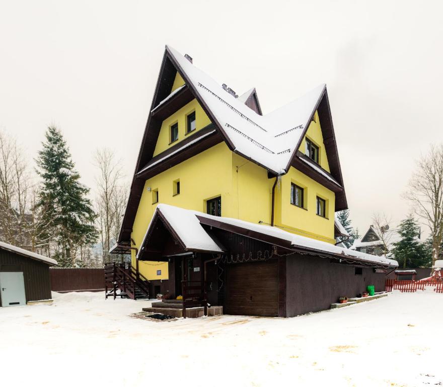 ザコパネにあるPokoje Banaśの雪屋根の大黄色い家