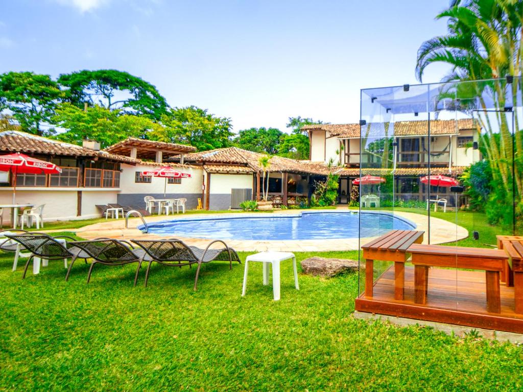 um resort com piscina, mesas e cadeiras em VELINN Pousada dos Marinheiros em Ilhabela