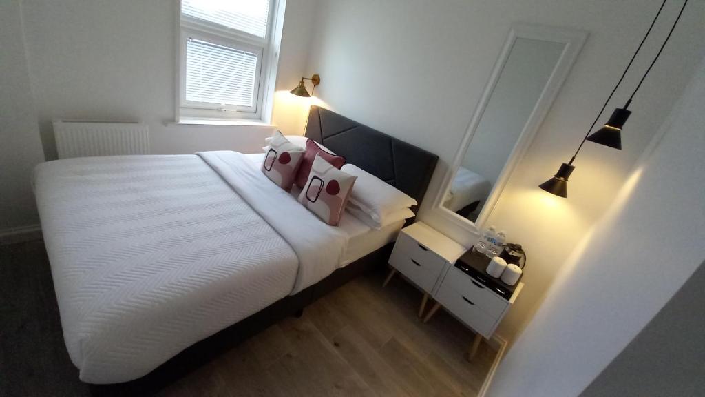 a bedroom with a large white bed with pink pillows at Home Away From Home in Kent