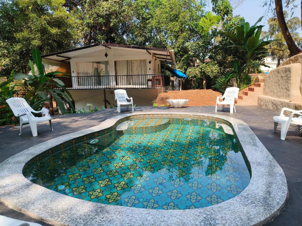 a small swimming pool with chairs and a house at Rooms in Greek Jungle Villa, Thalassa Road in Siolim