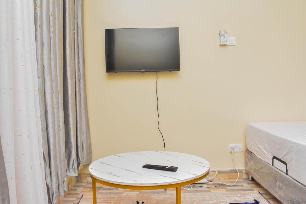 a room with a table and a tv on the wall at Evans' Cosy Studio Home in Mombasa