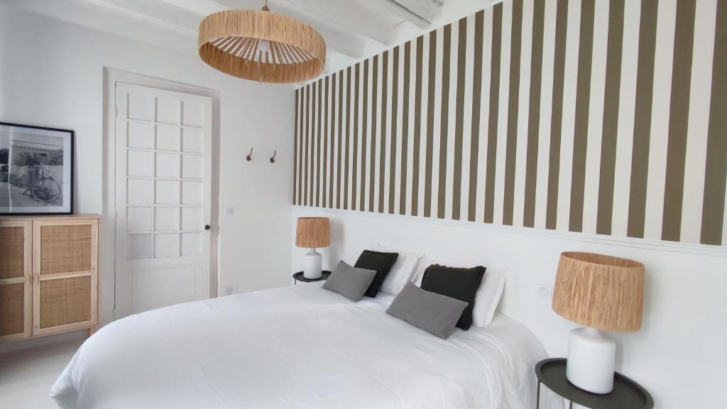 biała sypialnia z białym łóżkiem i 2 lampami w obiekcie Maison Charmeilles - Le studio Canon de Fronsac w mieście Fronsac