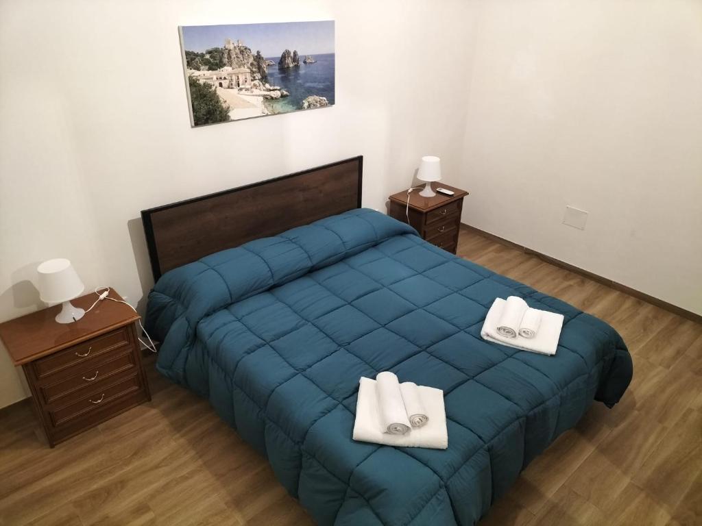 um quarto com uma cama azul com duas toalhas brancas em Scirocco e Maestrale em Petrosino