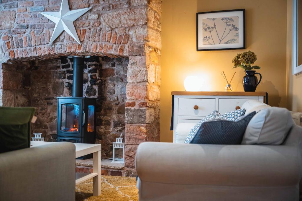 a living room with a couch and a brick fireplace at Blue House Berwick Upon Tweed in Berwick-Upon-Tweed