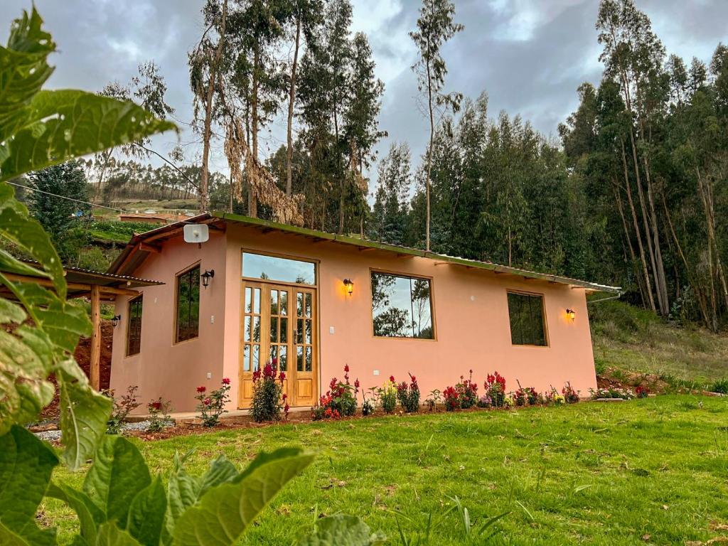una pequeña casa rosa en un campo con un patio en Linda Casa de campo frente a Laguna de Pacucha, en Pacucha