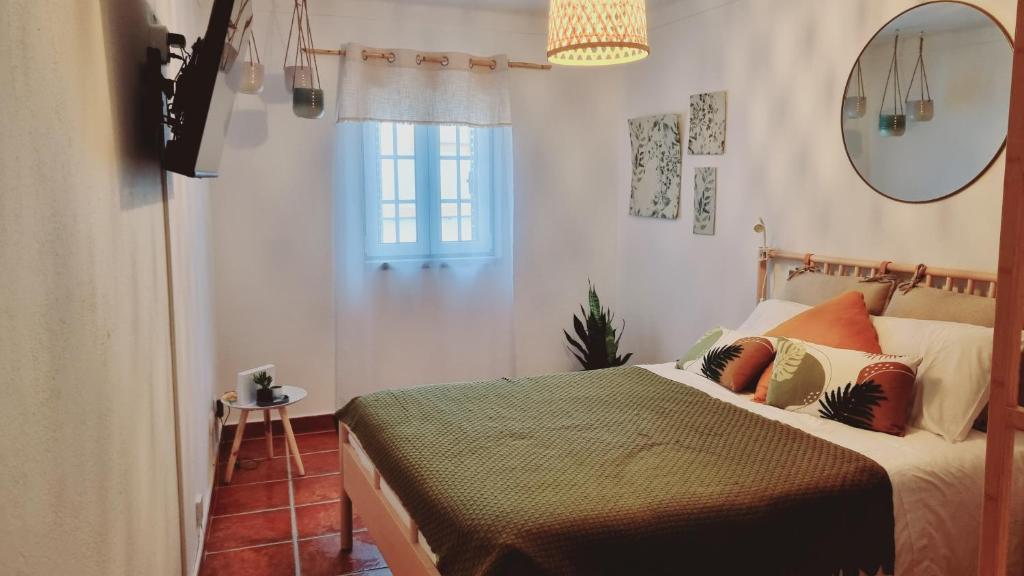 a bedroom with a bed and a mirror and a window at Cantinho da Vila by Portus Alacer in Alter do Chão