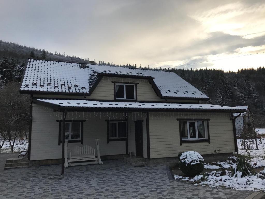 ein kleines Haus mit Schnee auf dem Dach in der Unterkunft Karpatske Vidlunnya in Mykulytschyn