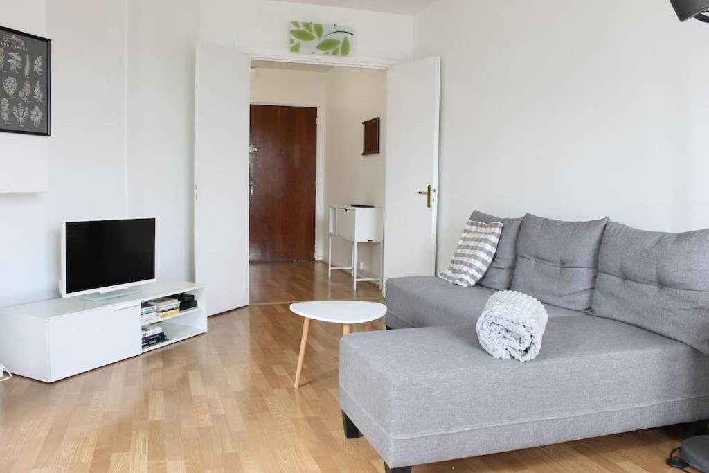 un soggiorno con divano grigio e TV di Appartement spacieux et lumineux - 15min de Paris Centre - Ideal Olympics a Sartrouville