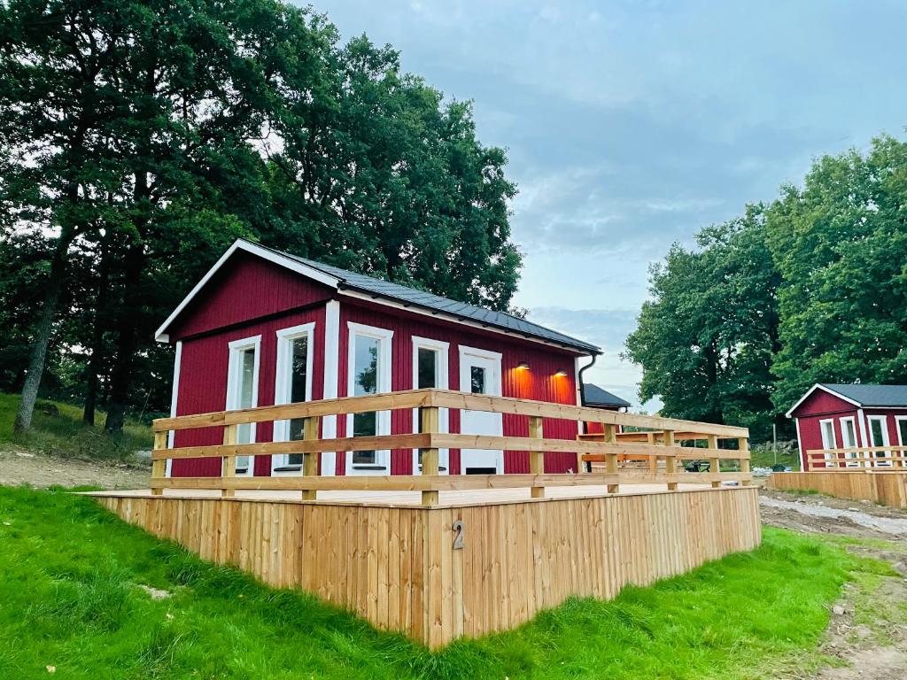 una pequeña casa roja con una valla de madera alrededor en Stuga - Ulvereds Hjorthägn en Laholm