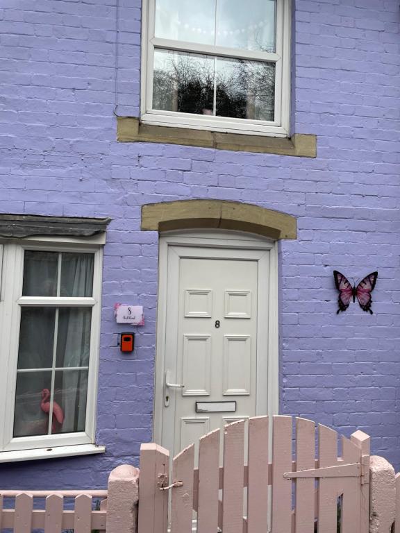 Llanfair Caereinion的住宿－Llanfair Caereinion house Quirky with river balcony，紫色的建筑,上面有一扇门和一只蝴蝶
