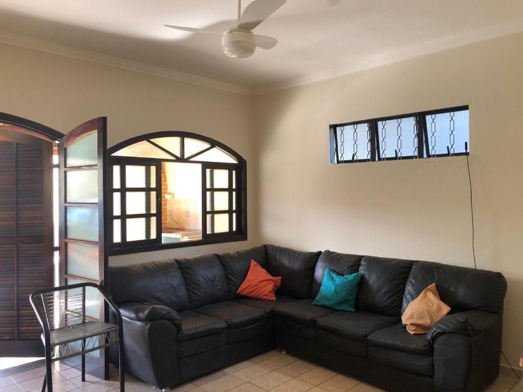 a living room with a black couch with colorful pillows at Casa grande com churrasqueira - Centro Ubatuba in Ubatuba