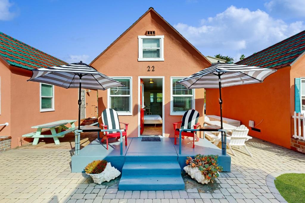 a patio with two chairs and two umbrellas at Sandcastle Cottage 22 in Oceanside