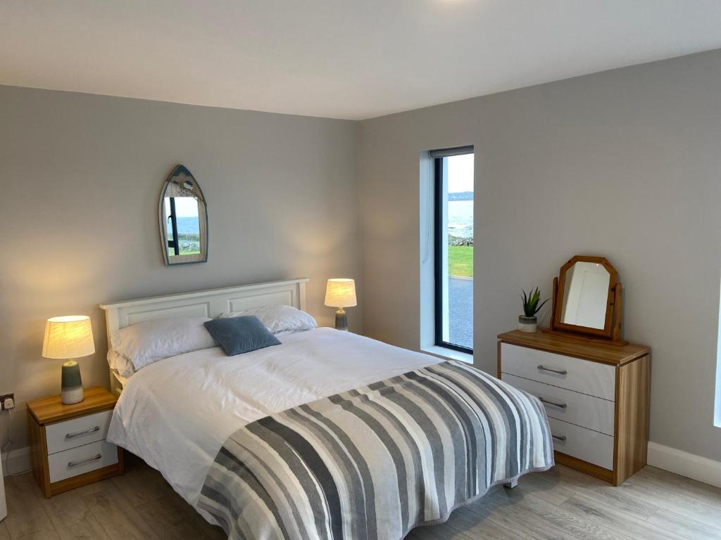 a bedroom with a bed and a mirror and a window at Spectacular ocean views & minutes to Cliffs- Clahane Shore Lodge in Liscannor