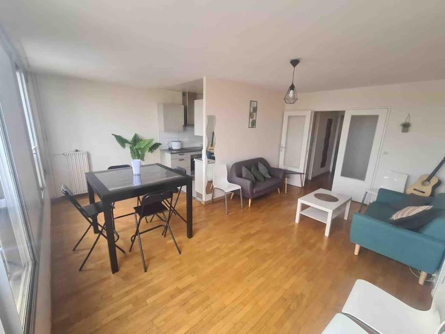 uma sala de estar com uma mesa e cadeiras e um sofá em Space and light for friends/family at Paris' door em Asnières-sur-Seine