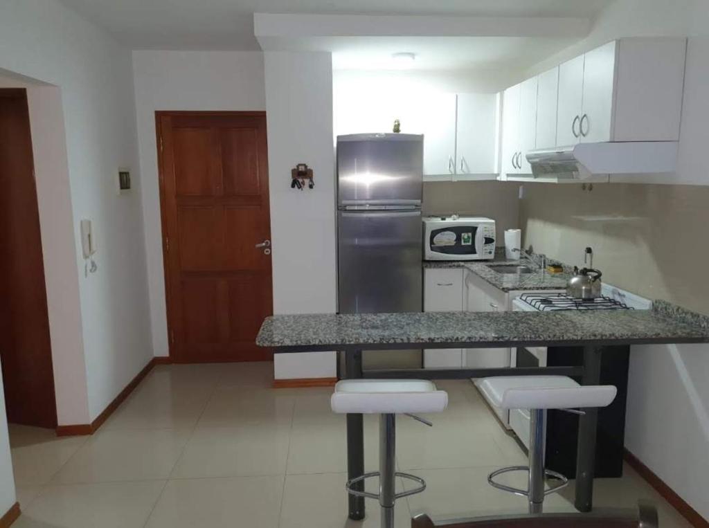 a kitchen with a counter with stools and a refrigerator at Departamento San José IV- Villa Carlos Paz in Villa Carlos Paz