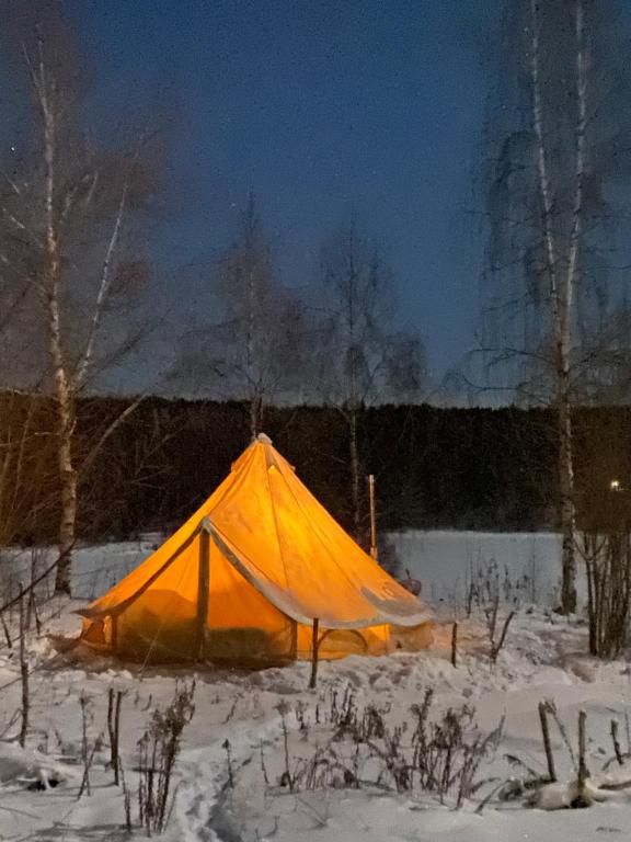 une tente orange dans la neige la nuit dans l'établissement Winter Glamping Tent Hovfjallet Vitsand, à Torsby