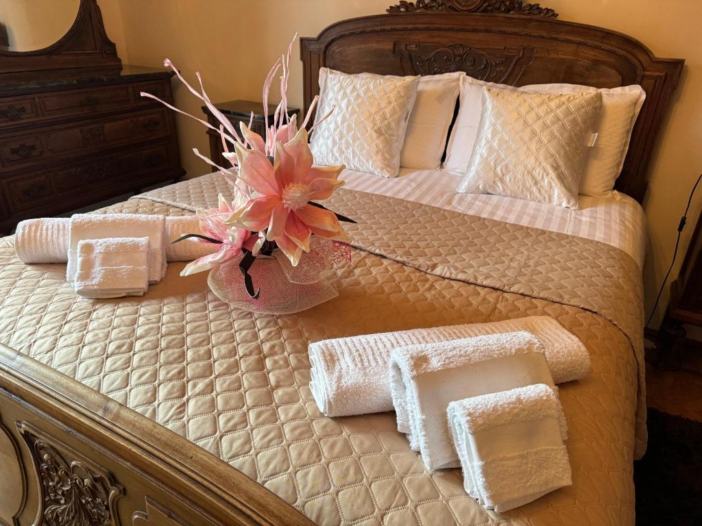 a bed with towels and a vase with a flower on it at Ca' Mariuccia appartamento in Venaria Reale in Venaria Reale