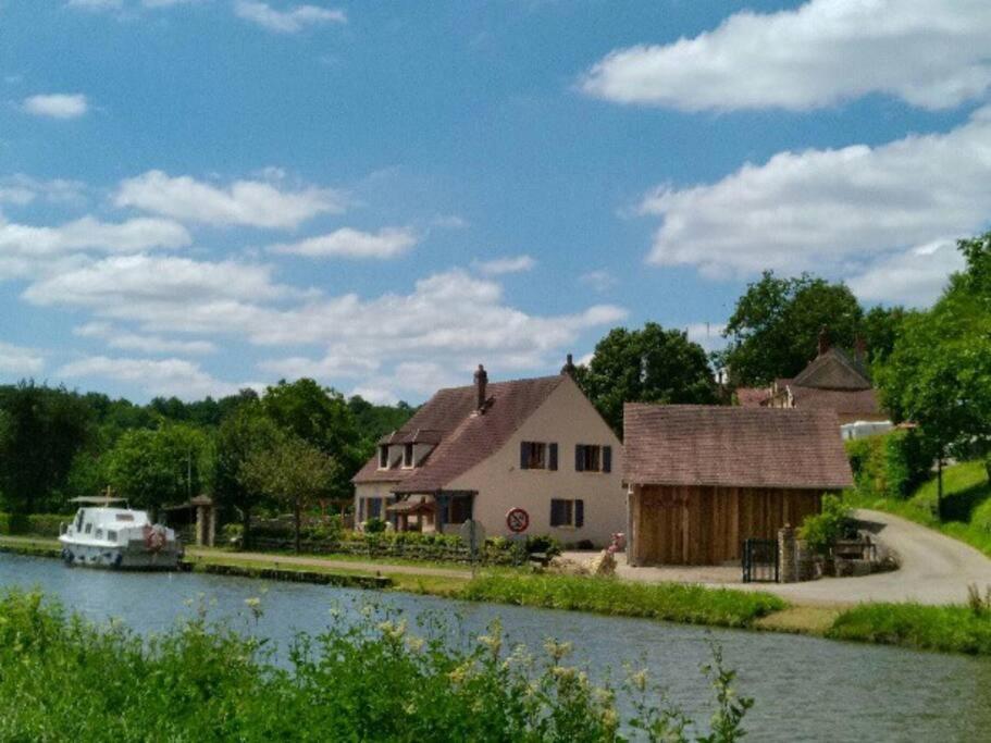 una casa junto a un río con un barco en Gîte du Flotteur, en Chevroches