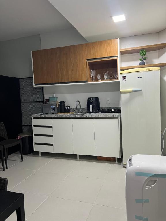 La cuisine est équipée de placards blancs et d'un réfrigérateur blanc. dans l'établissement Loft veraneio, à Balneário Camboriú